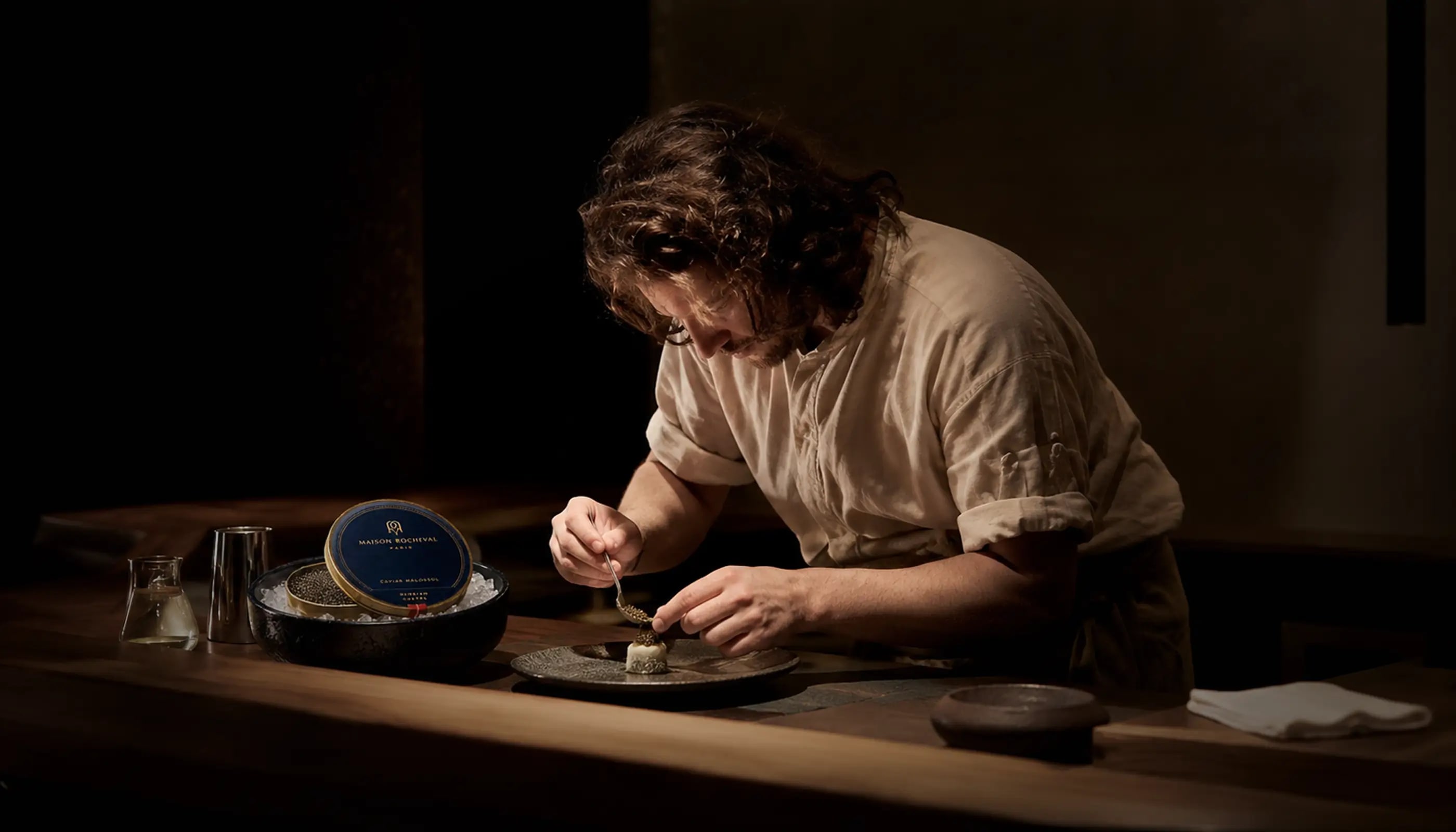 Maison Rocheval artisan preparing caviar at a dark dining counter