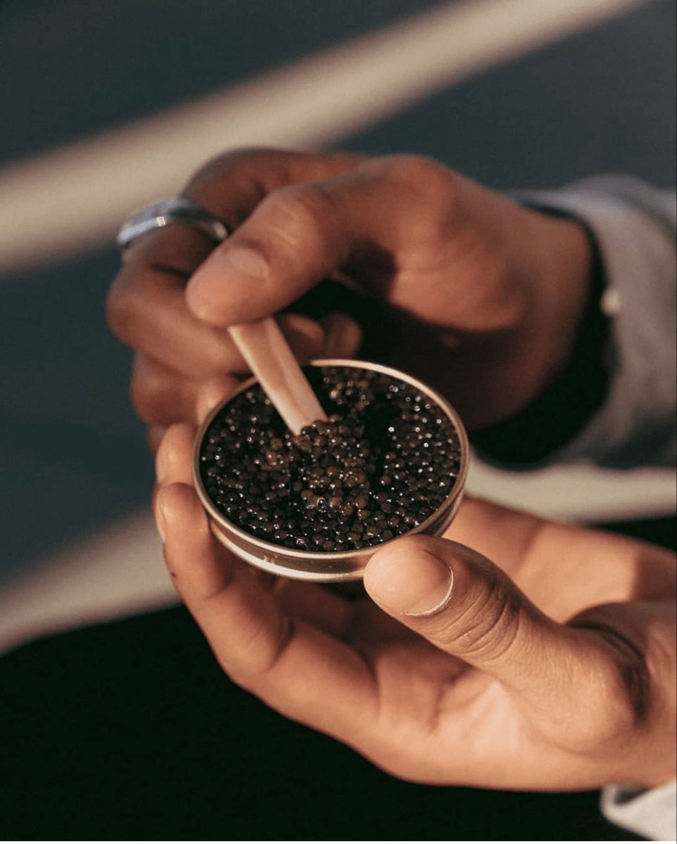 A caviar expert examining pearls in an open tin